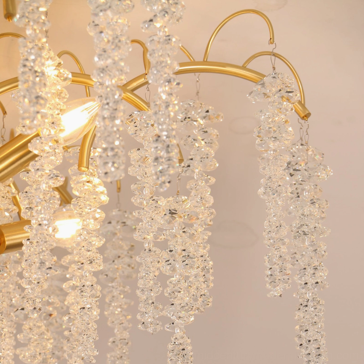 Emily Branch curved brass arm detail with lit candle bulb and dangling faceted crystal tassels showing romantic aesthetic