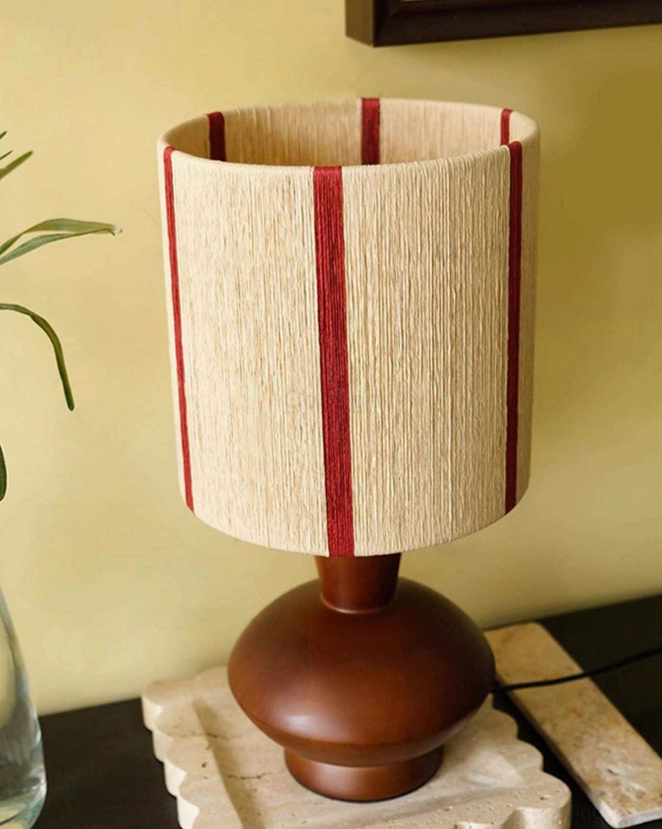 Ernest striped table lamp three-quarter view in corner interior design setting with complementary decorative elements