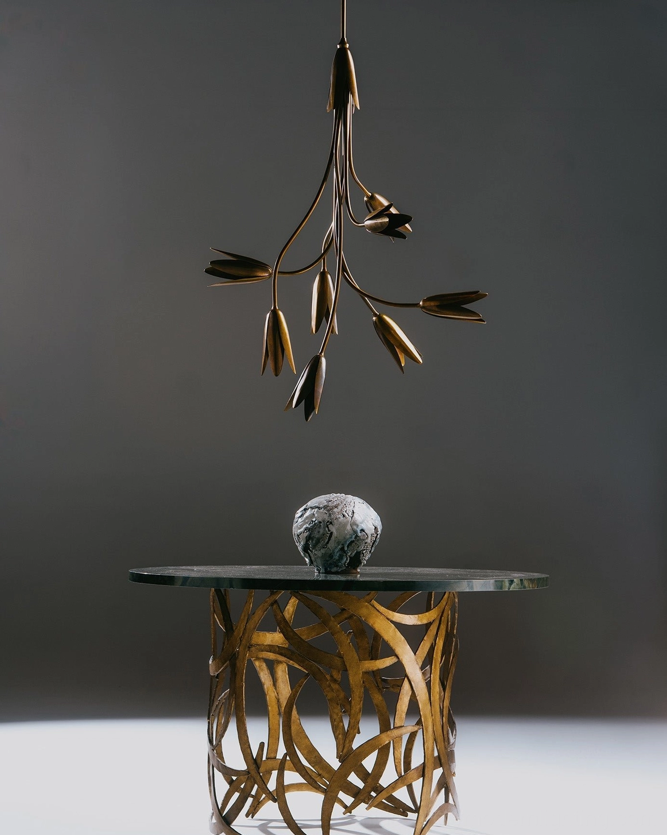 Evadne brass tulip chandelier in modern luxury interior with matching brass side table
