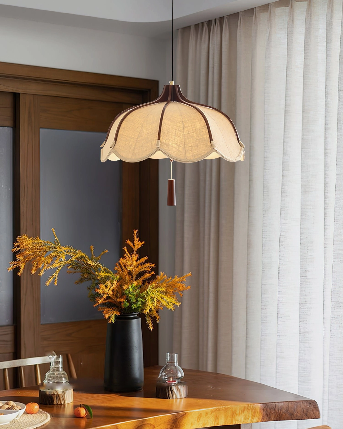 Evelyn mid-century pendant lamp above wooden dining table with floral centerpiece, side view in home setting