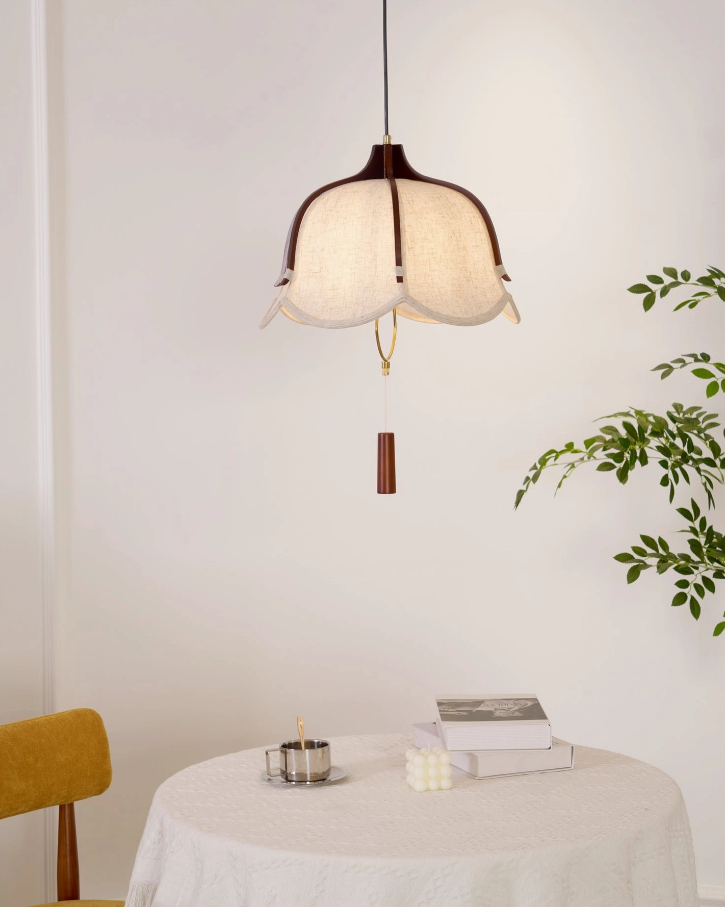 Evelyn pendant lamp illuminating minimalist dining area with white tablecloth and wooden storage cabinet