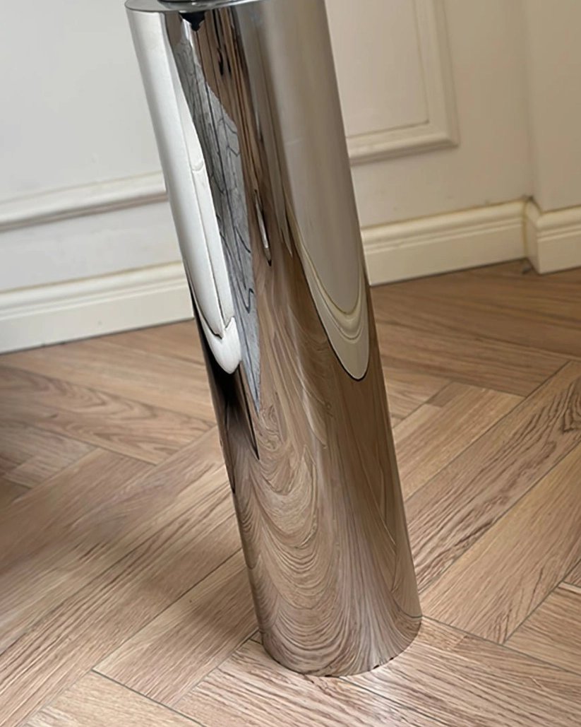 Detailed view of chrome floor lamp base and lower section with cylindrical metal components on wood flooring - industrial finish