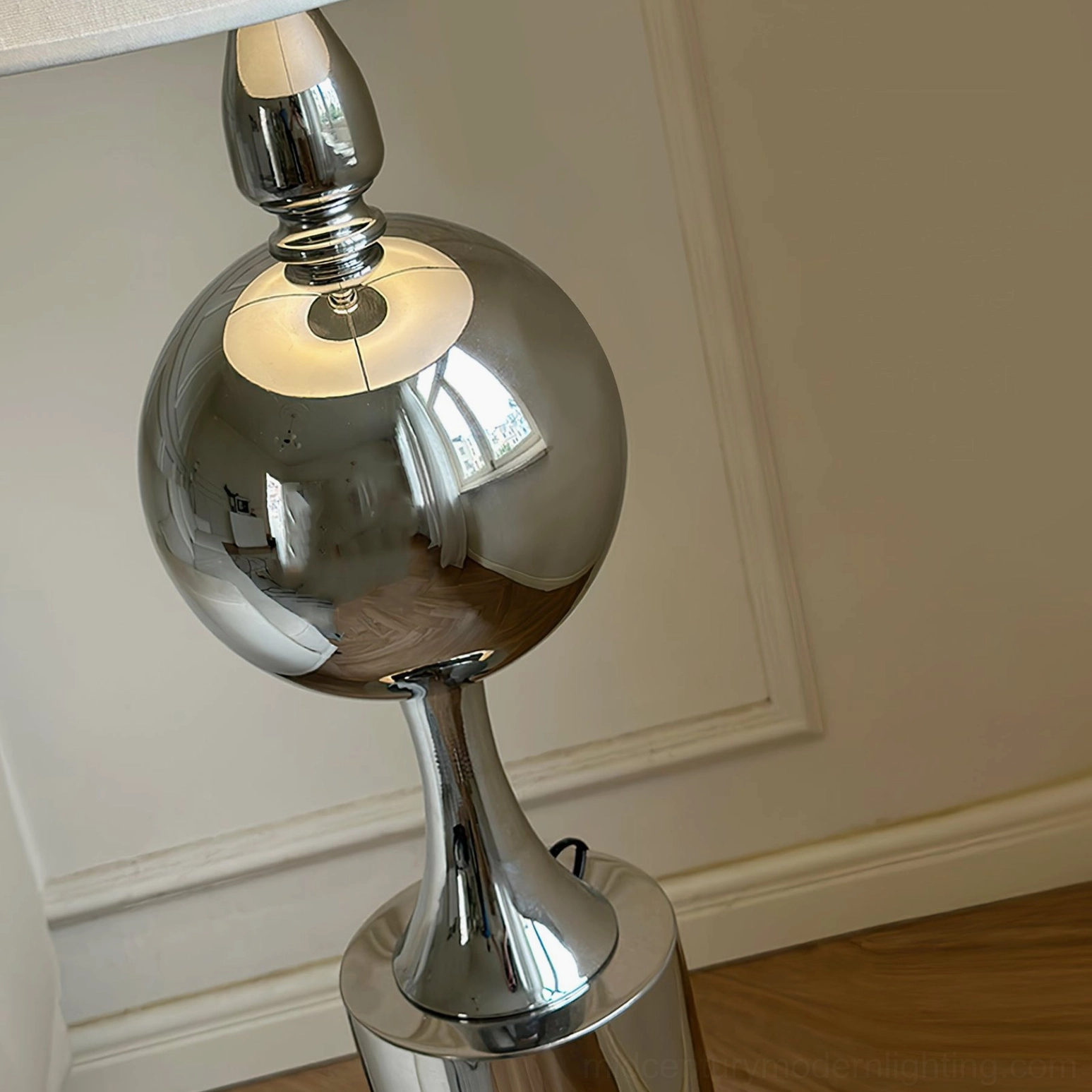Close-up detail of polished chrome spherical articulated joint showing reflective finish and precision engineering