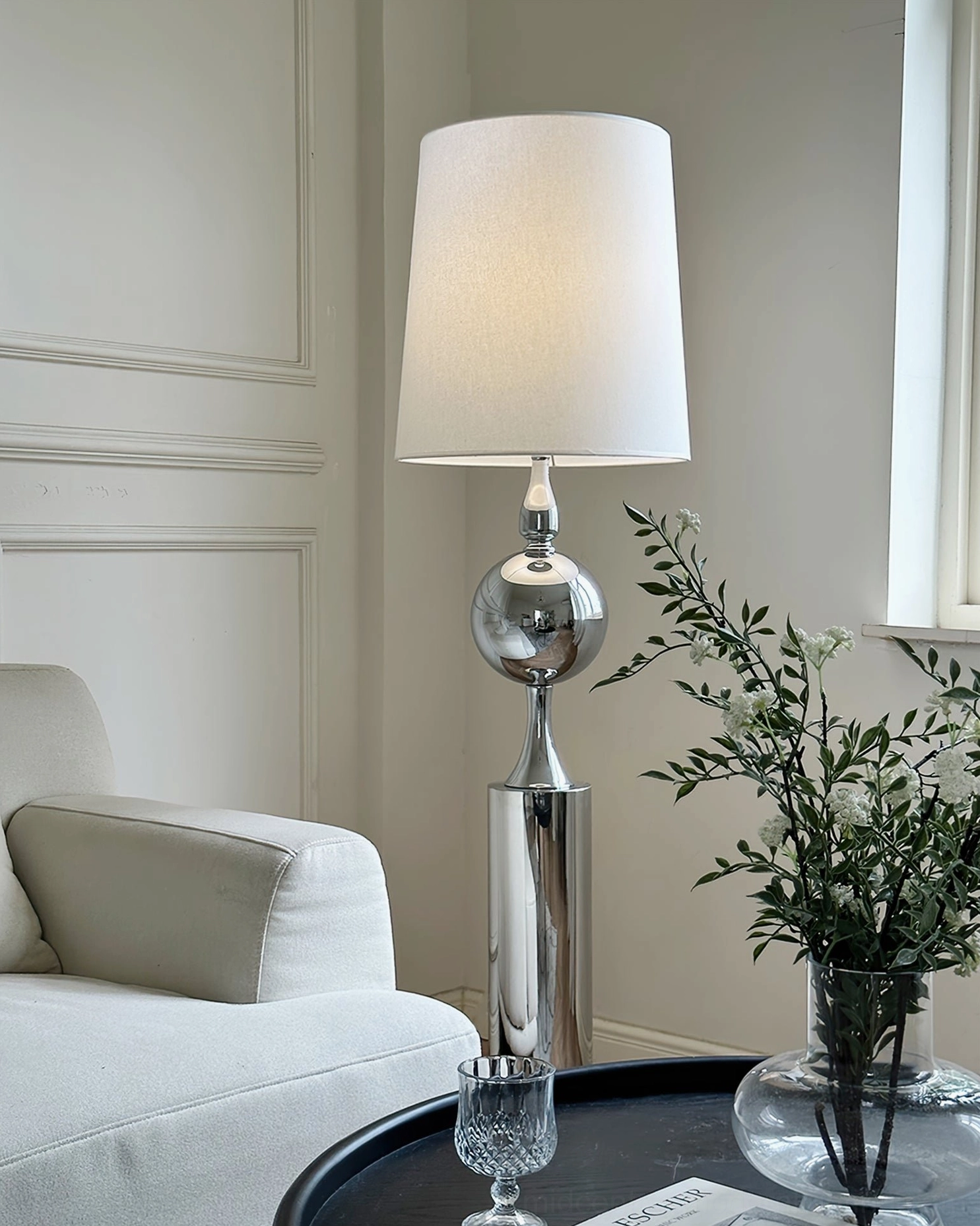 Sculptural floor lamp in cozy living space with decorative plants, glass vase, and black round coffee table - kinetic arm design