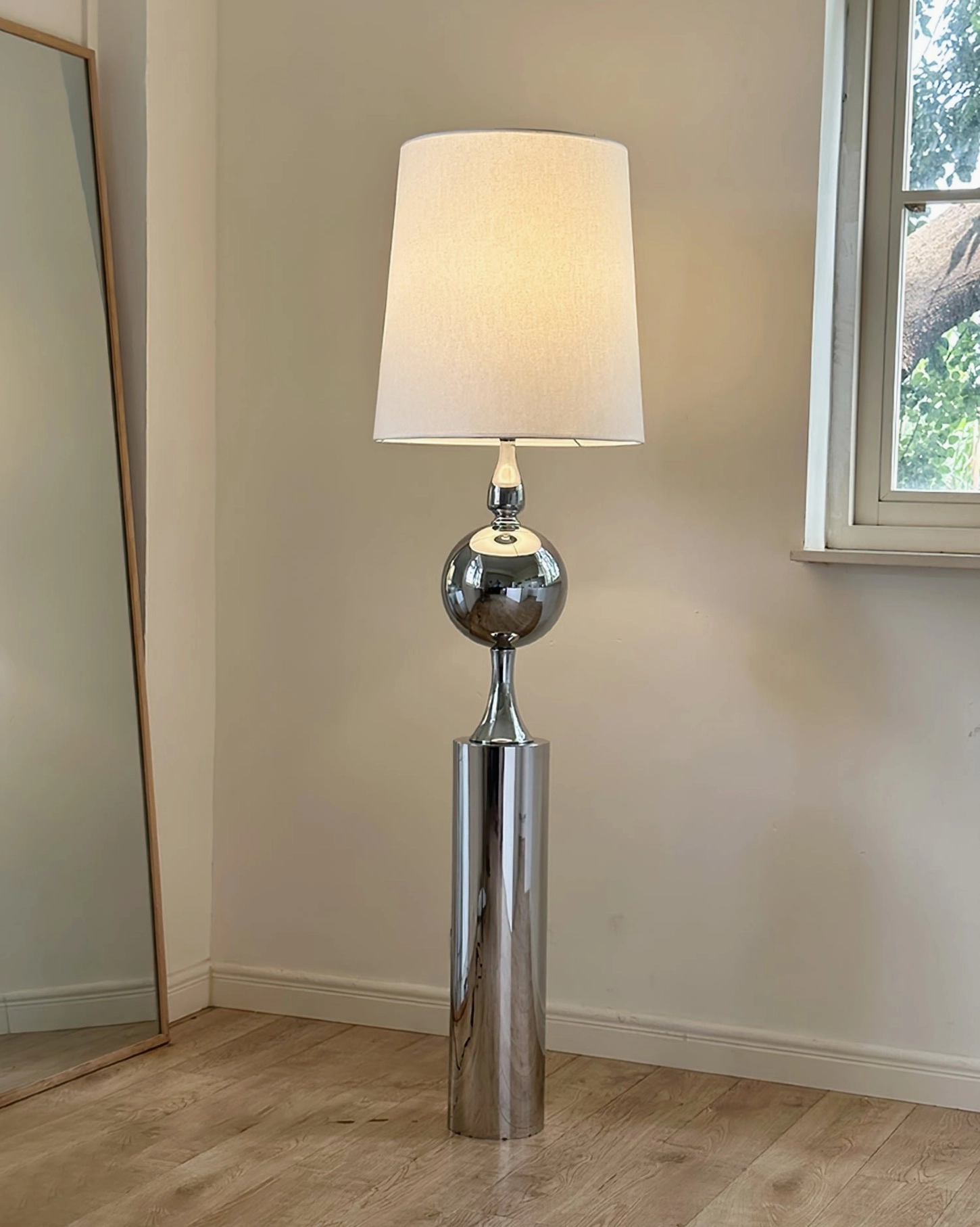 Side profile view of articulated floor lamp in corner with full-length mirror and window - showing adjustable arm positioning
