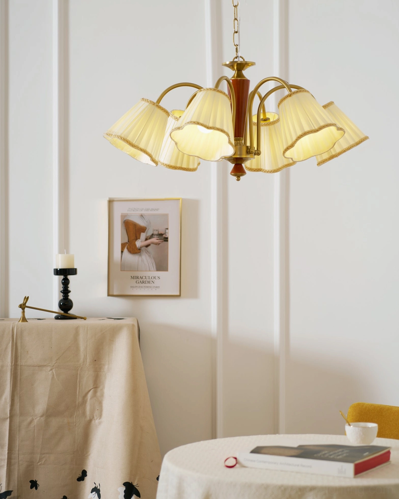 Florentine fabric chandelier lit in dining corner with wall art and candle holders, warm yellow glow and pastoral retro style