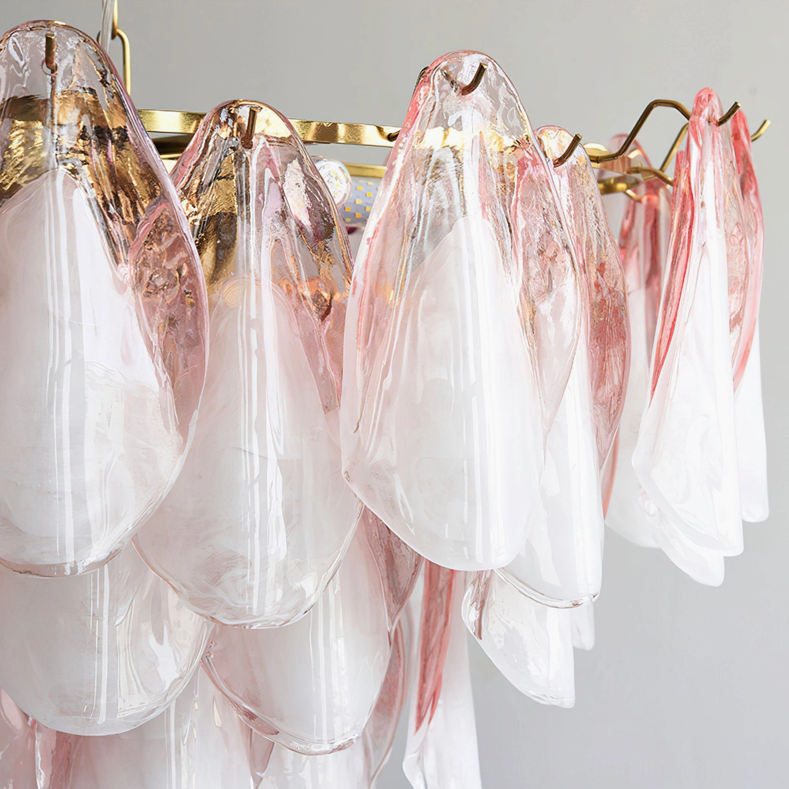 Close-up detail of pink and white translucent glass petals with gold metal frame