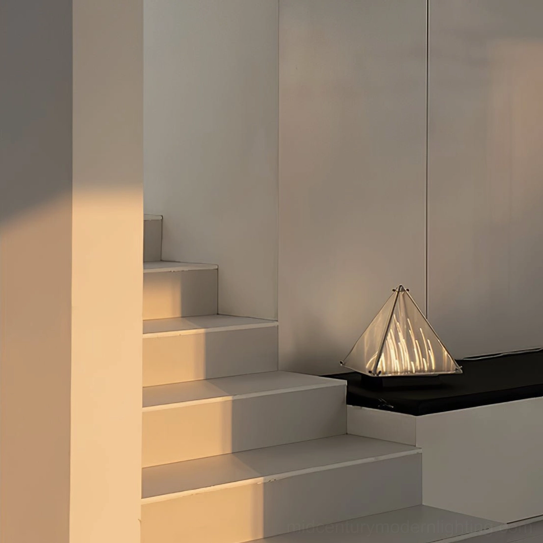 Geometric pyramid lamp with warm glow on black platform in modern indoor stairwell side view