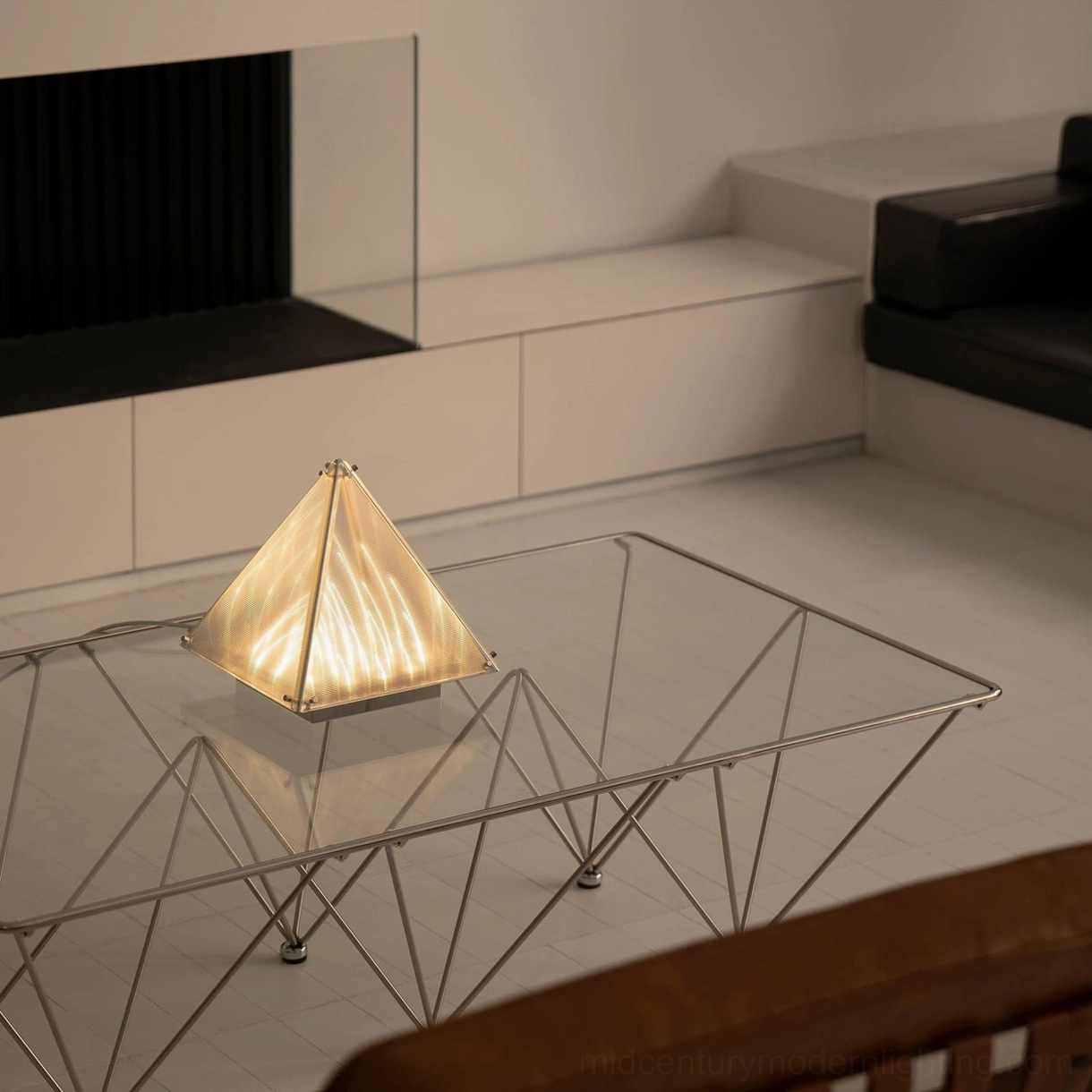 Modern pyramid table lamp creating warm ambient lighting in contemporary minimalist living room setting
