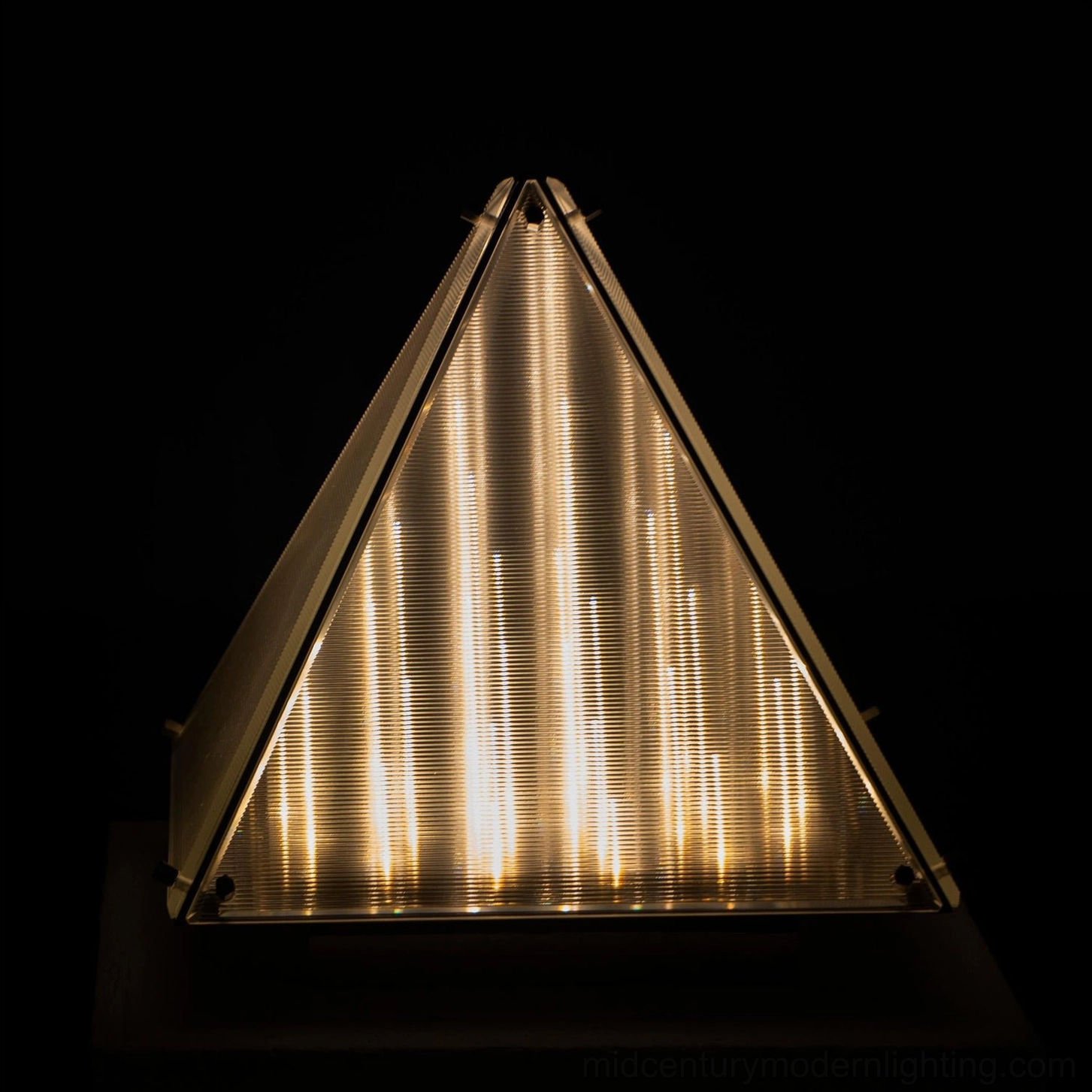 Fragment geometric pyramid lamp in sculptural lighting role within interior design composition
