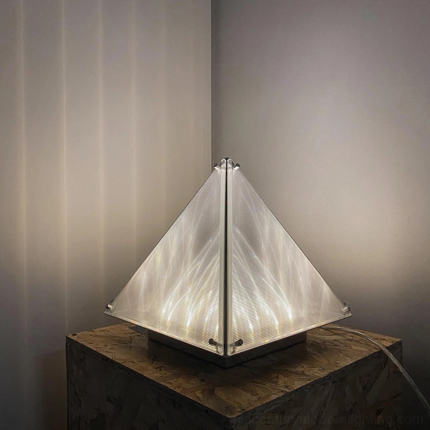 Pyramid table lamp creating architectural shadow patterns and geometric light play on surfaces