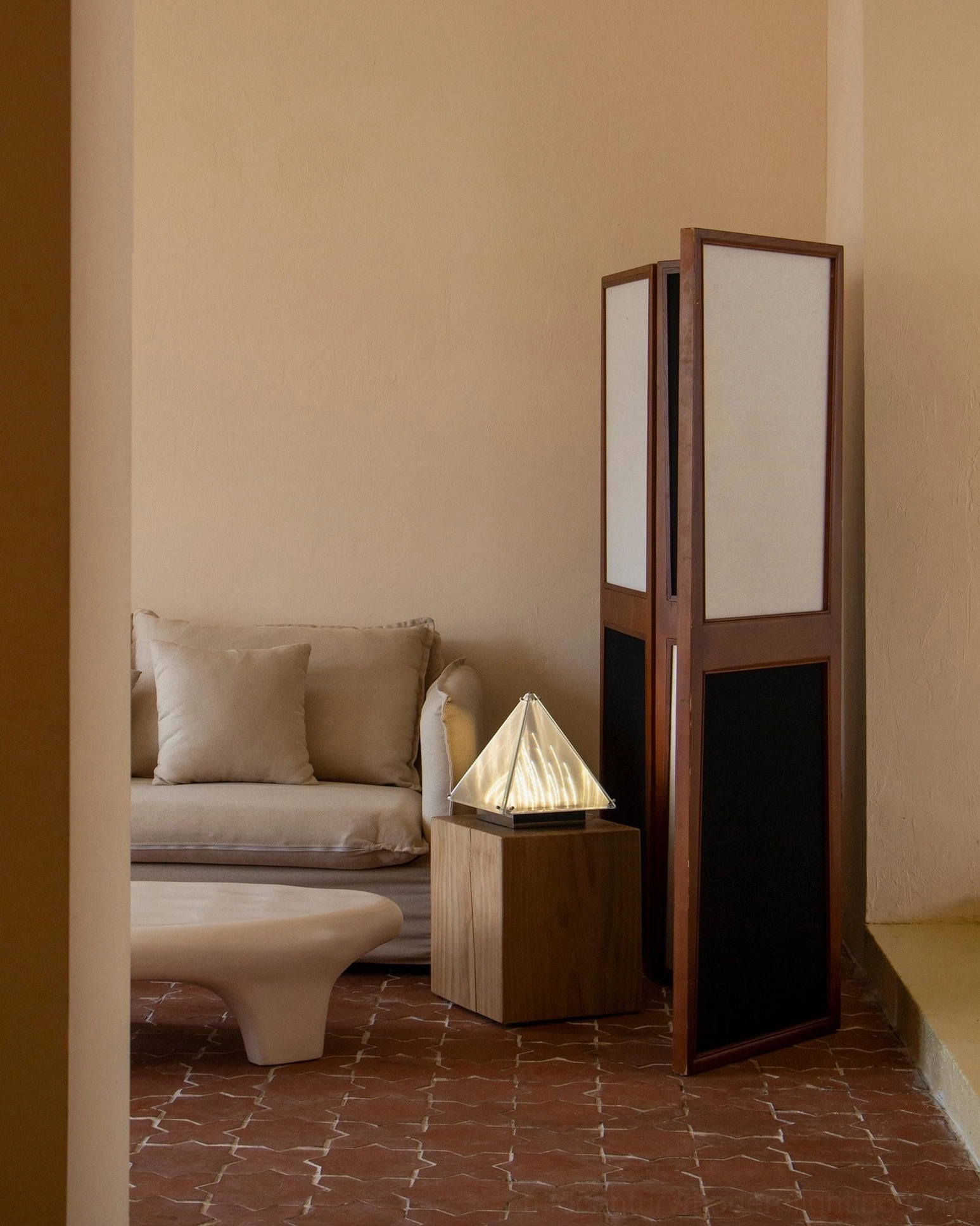 Modern pyramid table lamp on wooden side table beside contemporary fabric sofa lounge