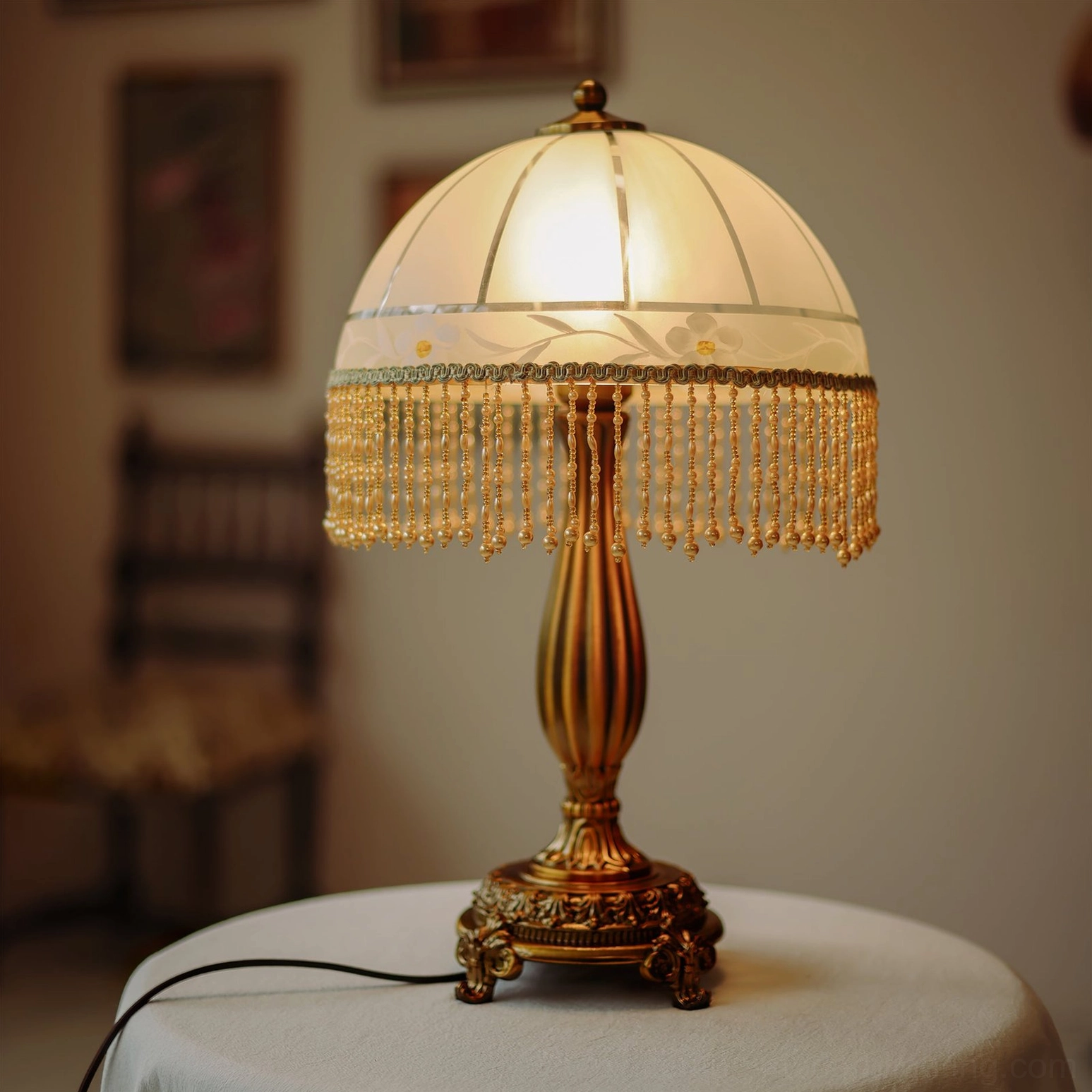 Illuminated tassel flower lamp with frosted glass shade casting soft glow on round fabric side table in vintage interior