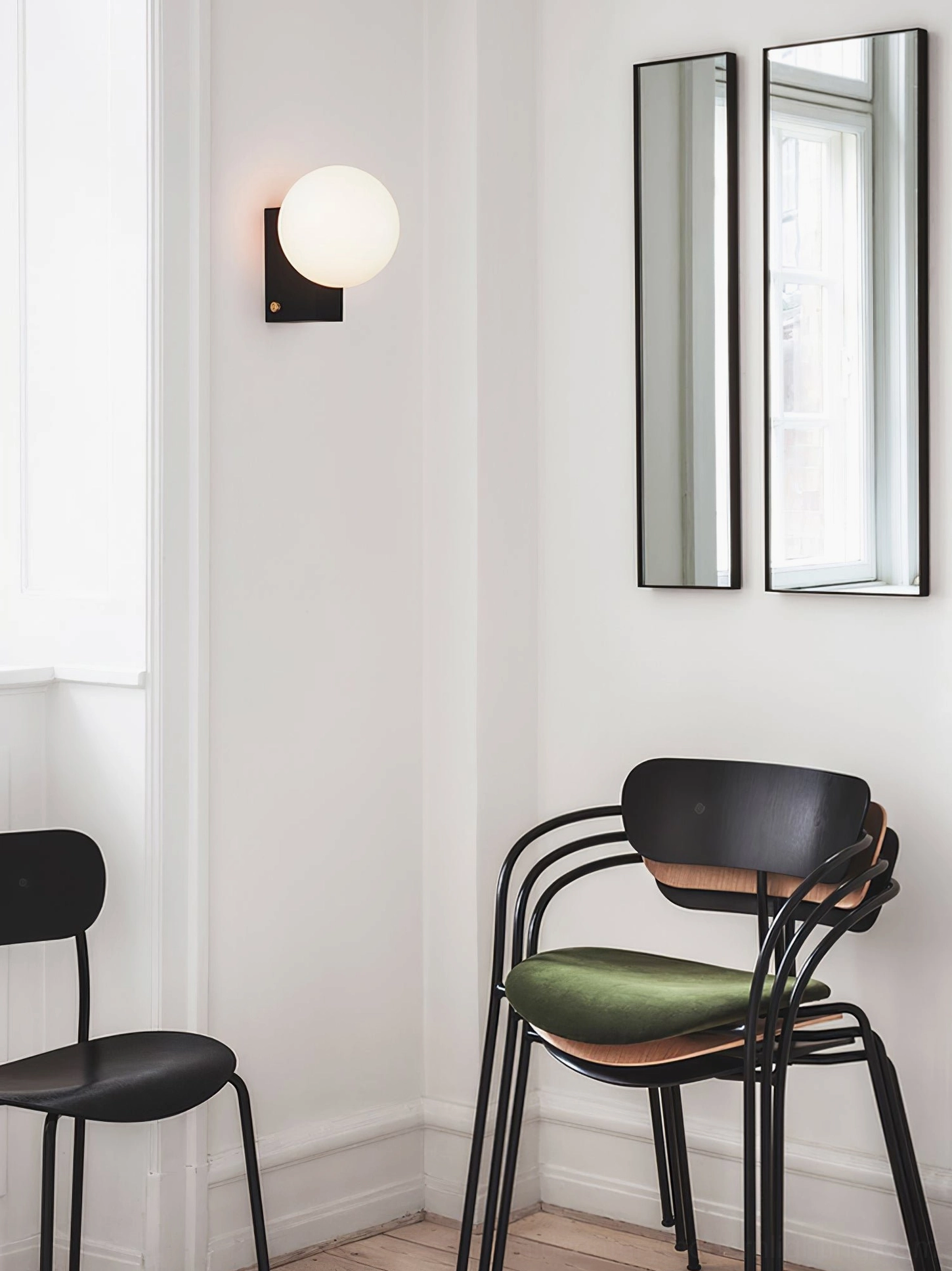 Frosted glass globe wall sconce with precision metal mounting bracket showcasing modern minimalist design principle