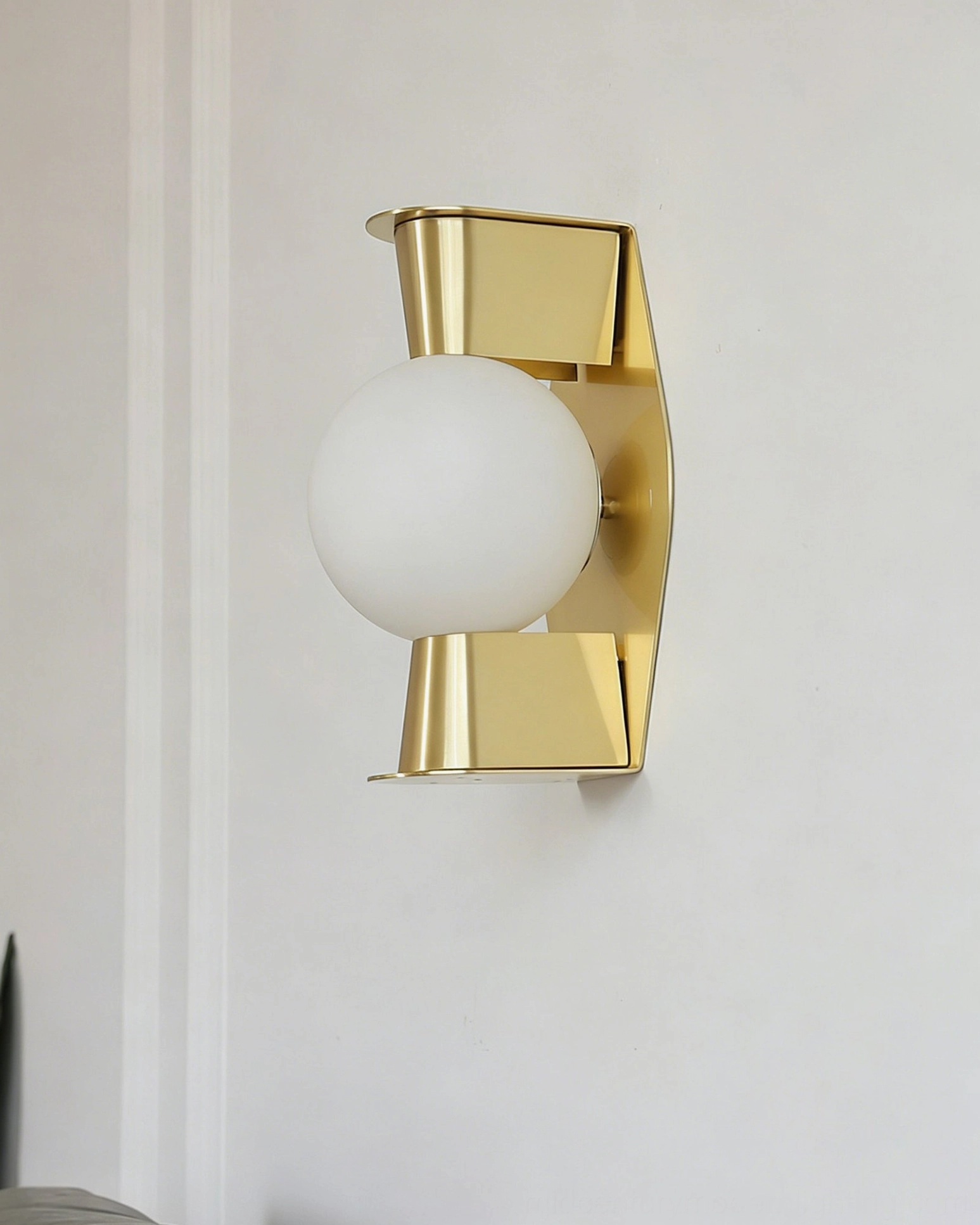Gale Globe Wall Sconce mounted on residential wall corner, unlit frosted glass globe with brass fixture in situ