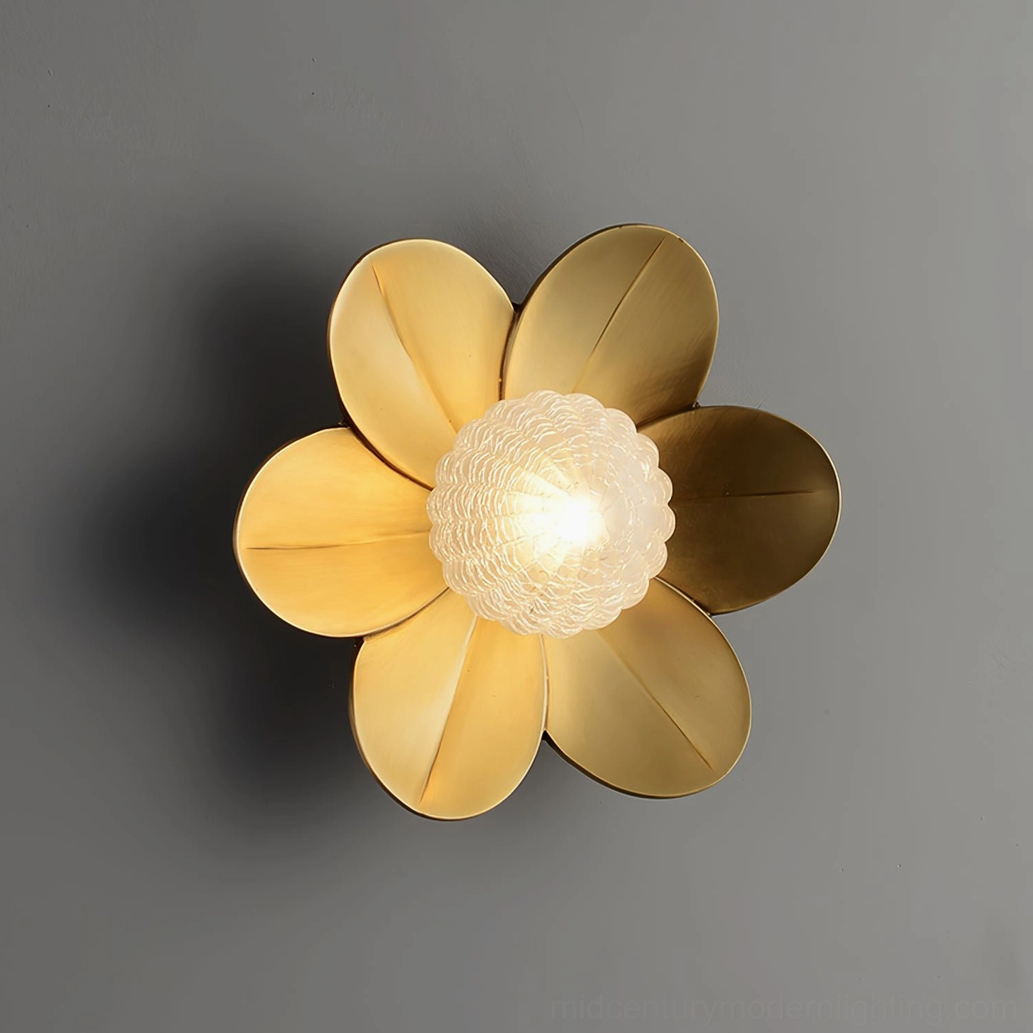 Gigi wall sconce close-up with warm gold metal petals and bright illuminated frosted glass