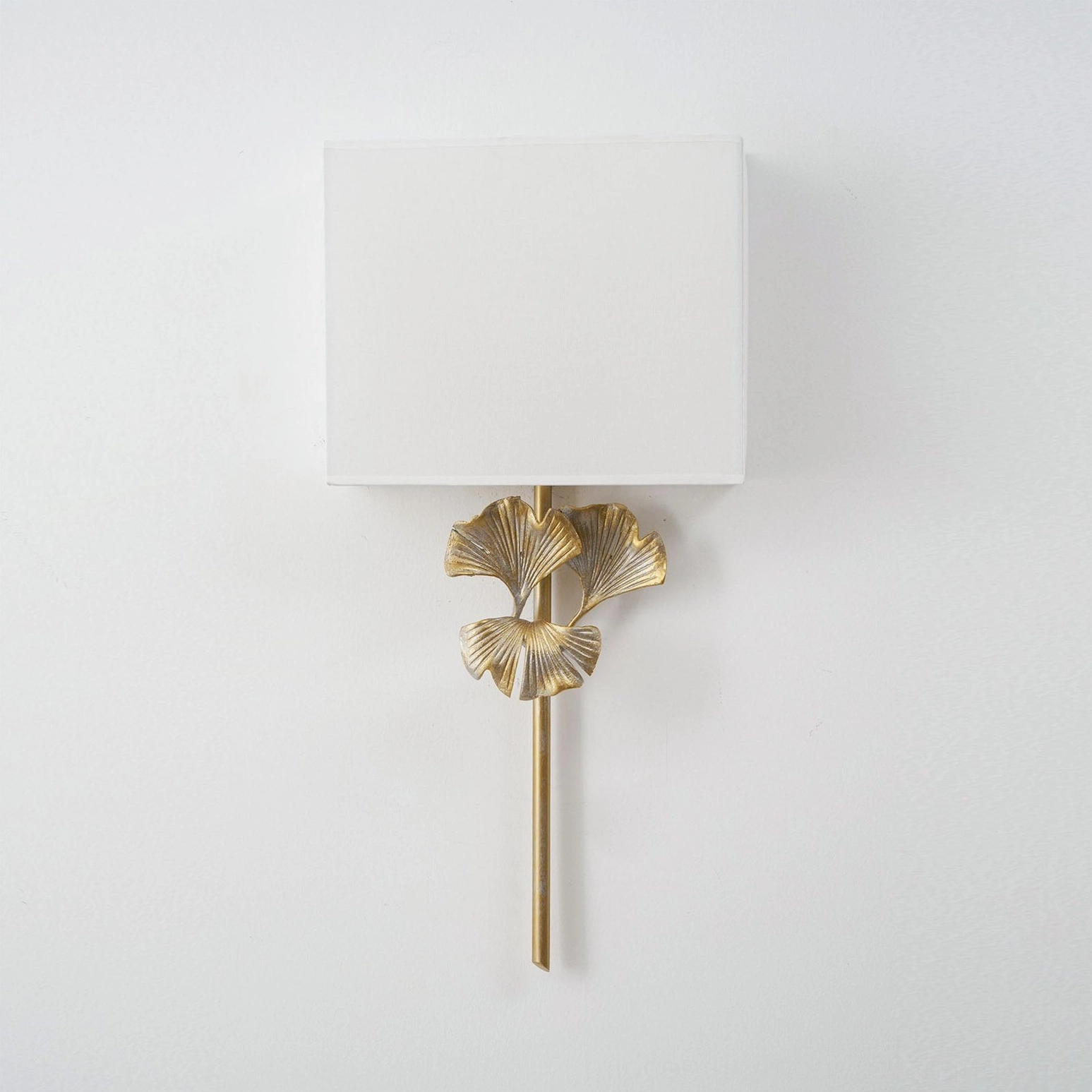 Antique brass gingko sconce mounted symmetrically with minimal wall art installation