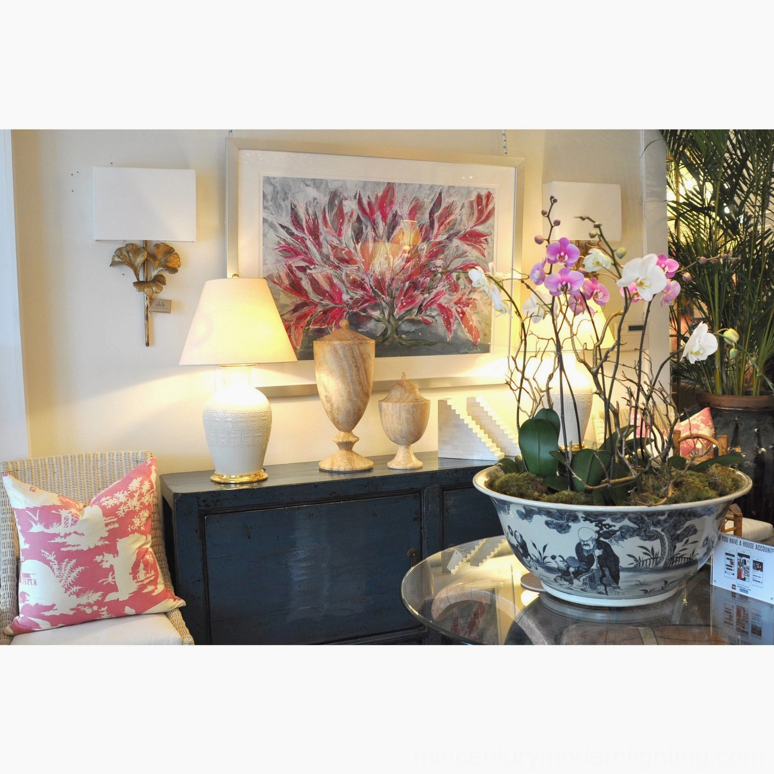 Gold gingko sconce in lounge with decorative sideboard, table lamps and potted flowers