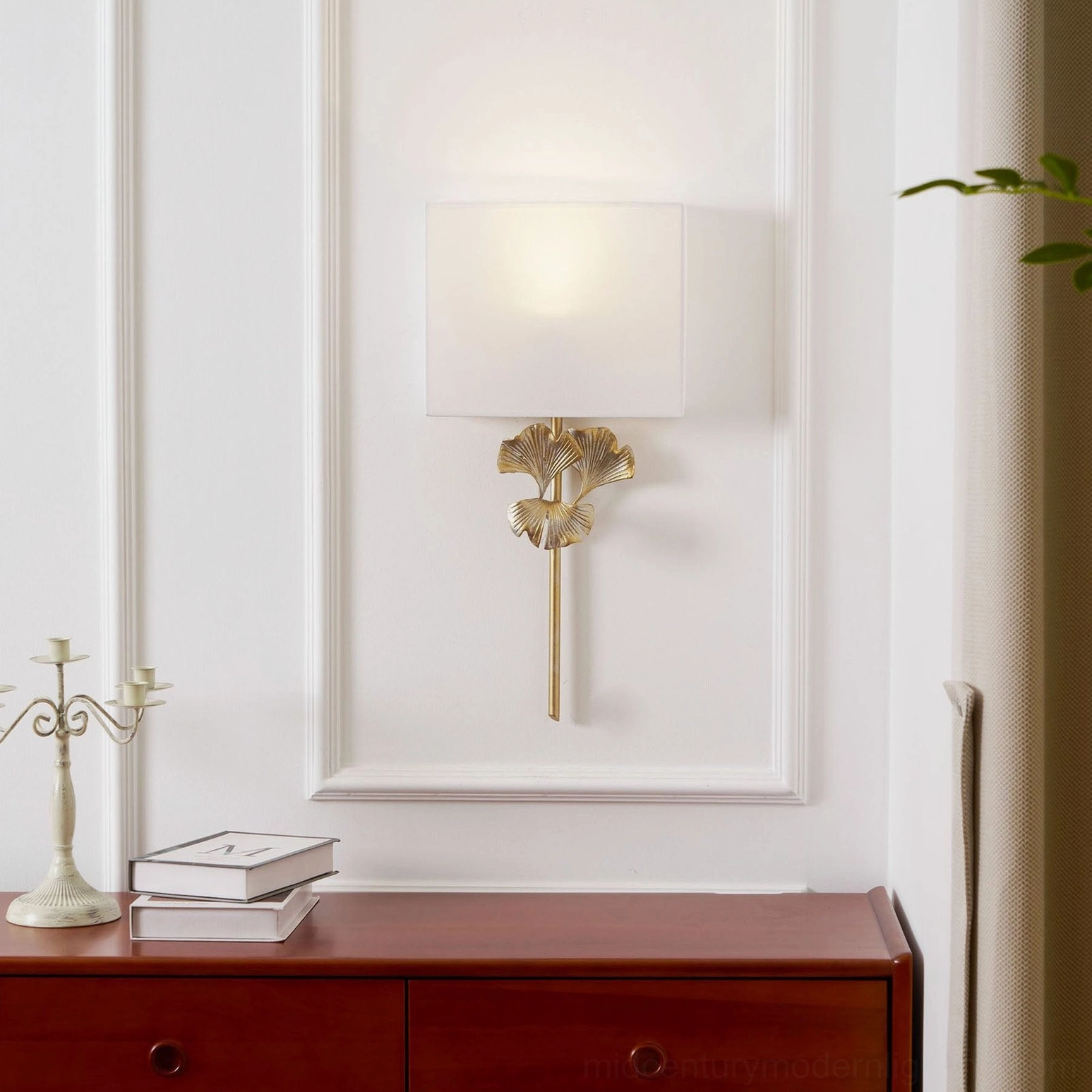 Lit gold brass gingko wall lamp in minimalist entryway with wooden console table