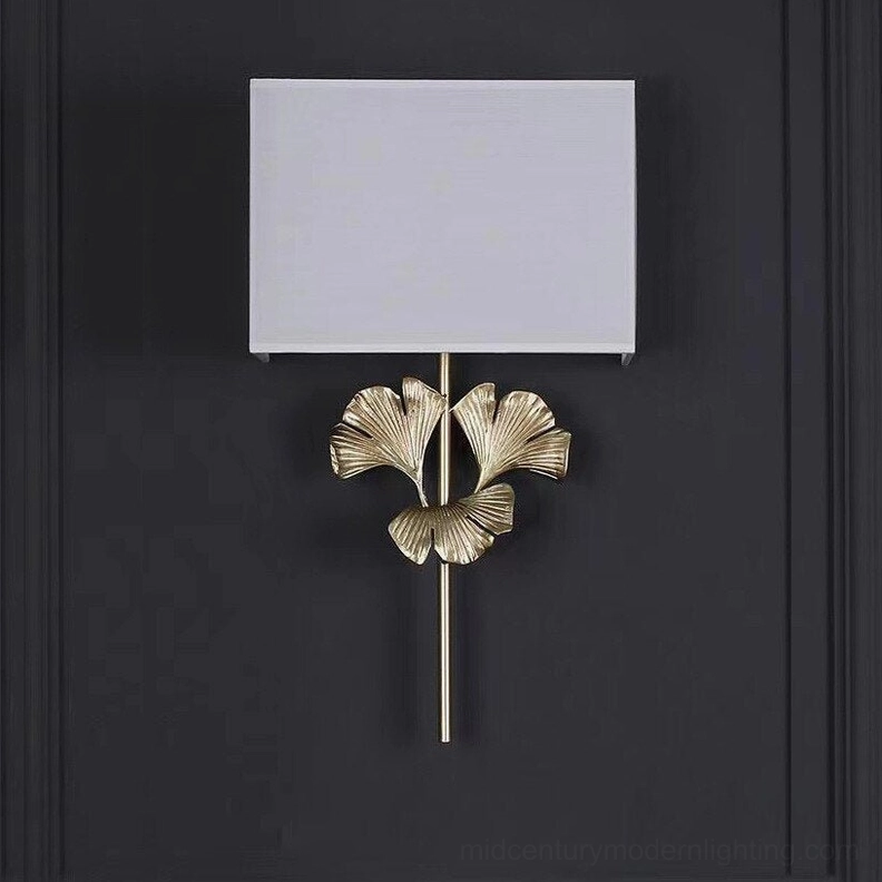 Silver-toned gingko wall sconce mounted on dark gray accent wall, unlit shade