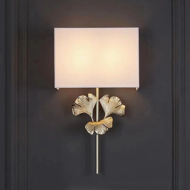 Illuminated silver gingko leaf wall lamp on dark accent wall creating warm ambient light