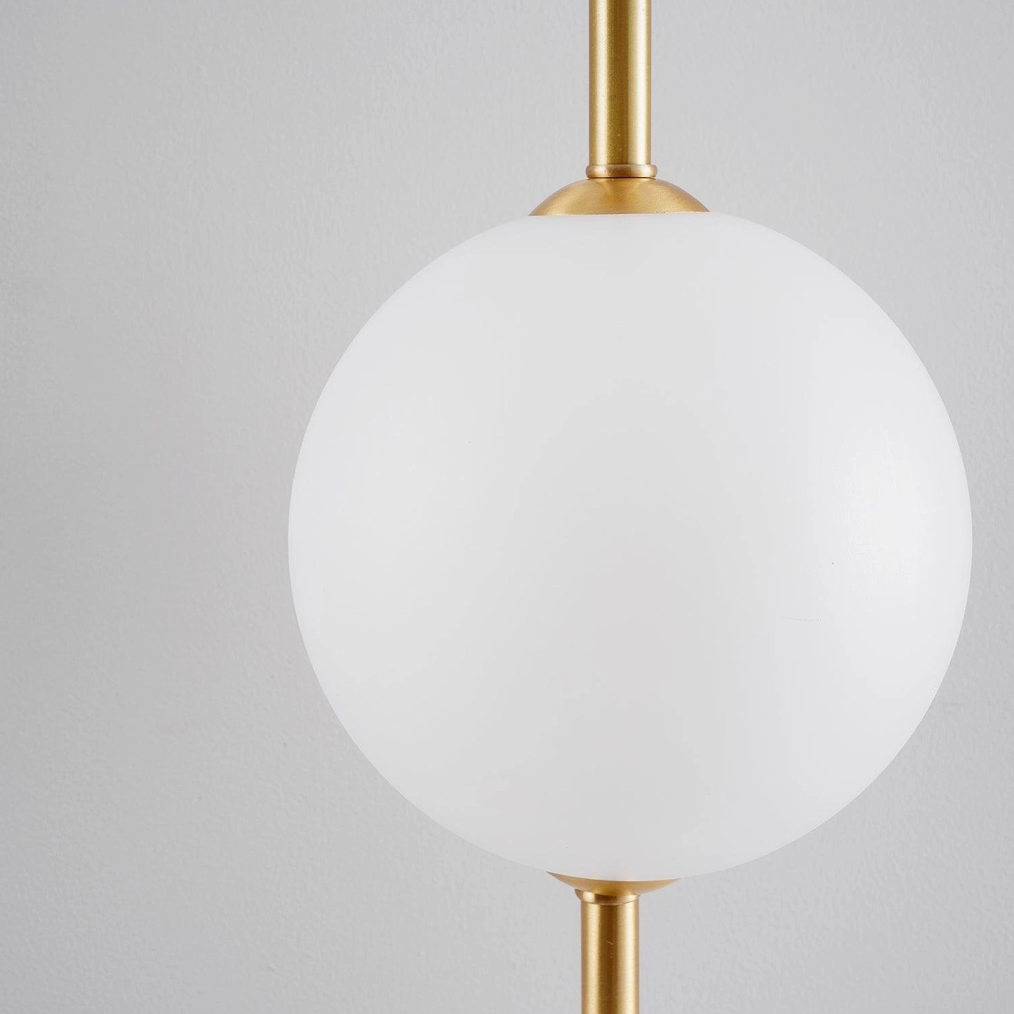 Single large frosted white globe lampshade with brass mounting hardware, low-angle shot