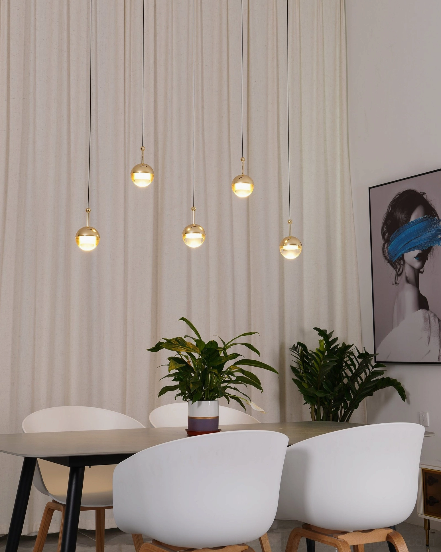 Gold spherical pendant light set in bright modern dining room with sheer curtains warm minimalist decor