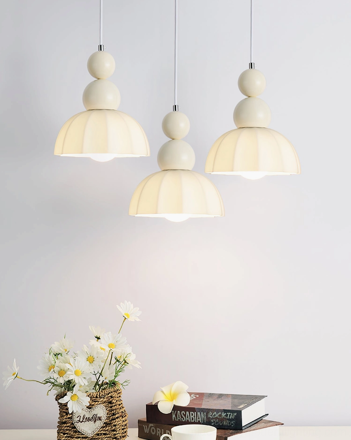 Three gourd bubble pendant lights hung at varying heights over decorative shelf with flowers and books, warm illumination