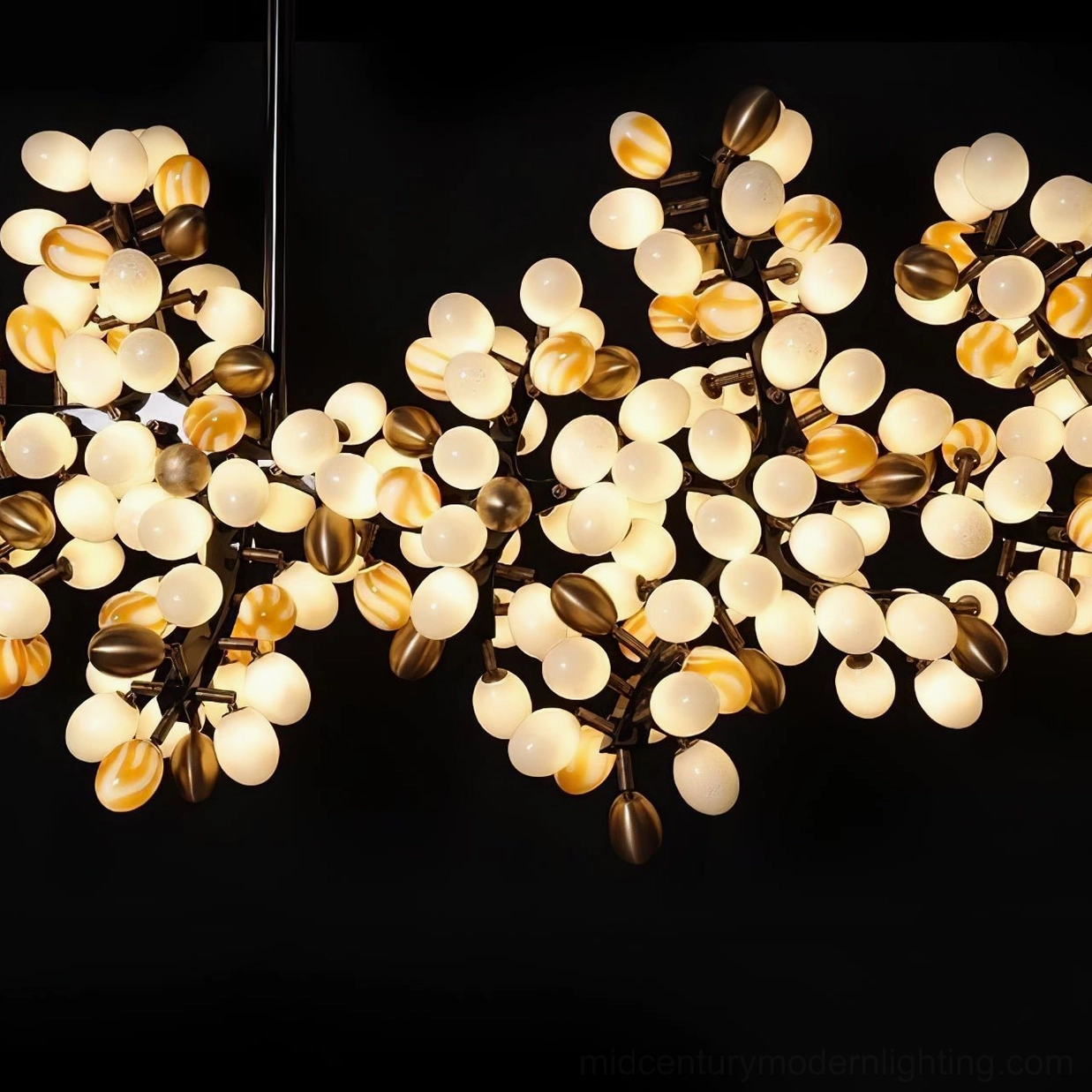 Close-up macro detail of grape cluster chandelier showing warm glowing frosted glass orbs and brass metal branches