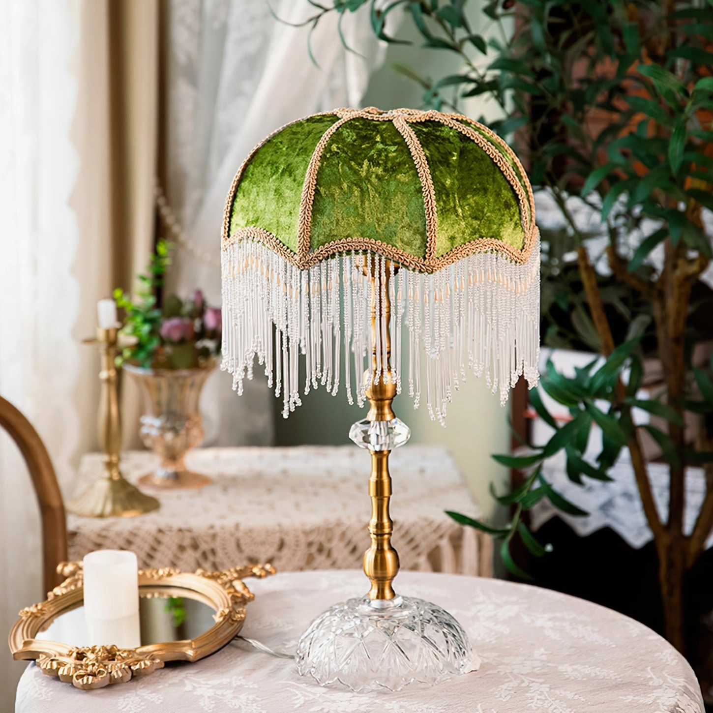 Green shade fringed table lamp displayed on vintage lace dining table with potted plants