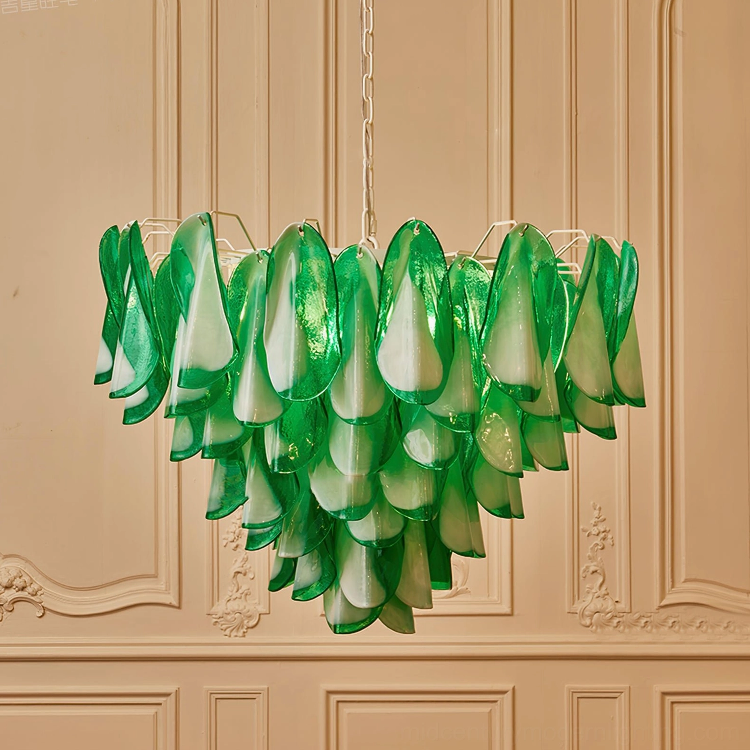 Green art glass chandelier side view against carved beige wall, showing petal arrangement and polished glass finish details