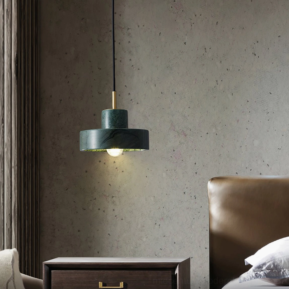 Dark green marble pendant light hung low in luxury bedroom with concrete wall and brass details
