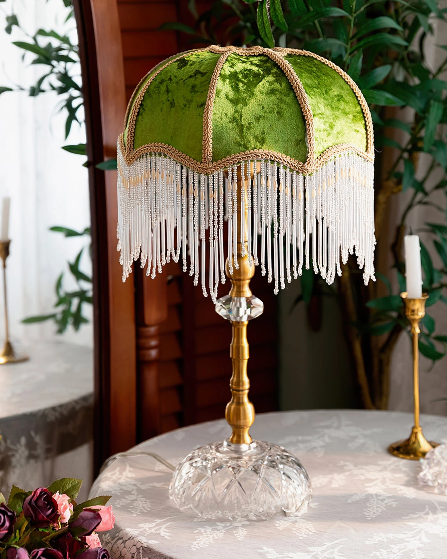 Green velvet fringed table lamp with cut crystal base and brass stand on wooden table