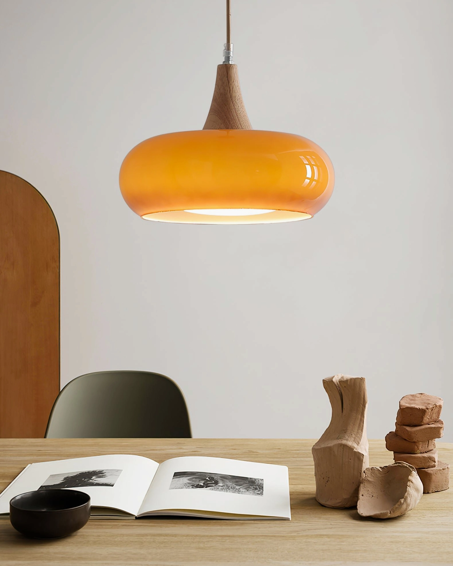 Hailie pendant lamp installed above mid-century dining table, warm amber glow detail shot