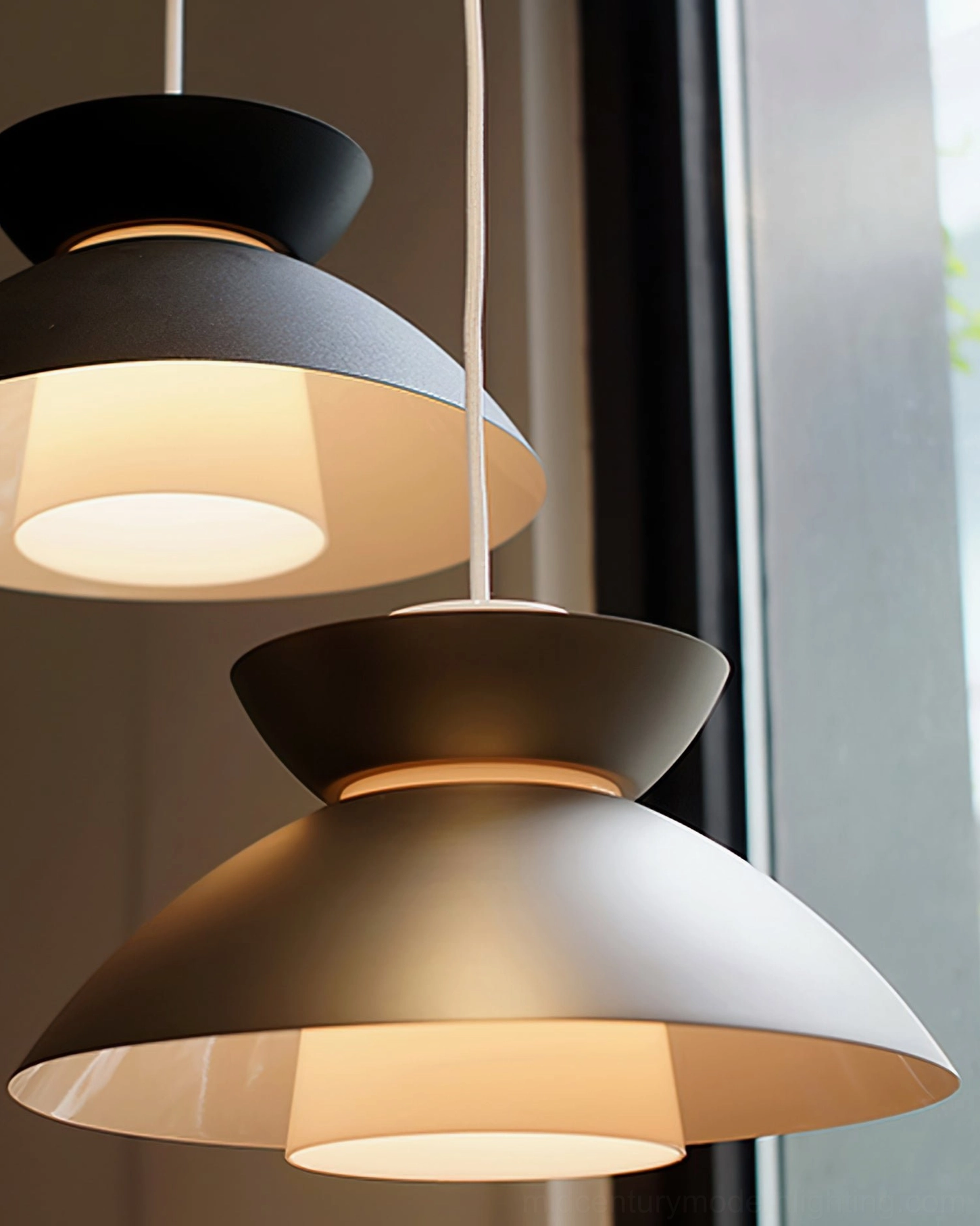 Two layered Hannes pendant lamps with warm interior illumination, indoor side view near large window
