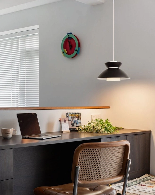 Single Hannes modern pendant lamp suspended in home office workspace above desk with furniture and decor