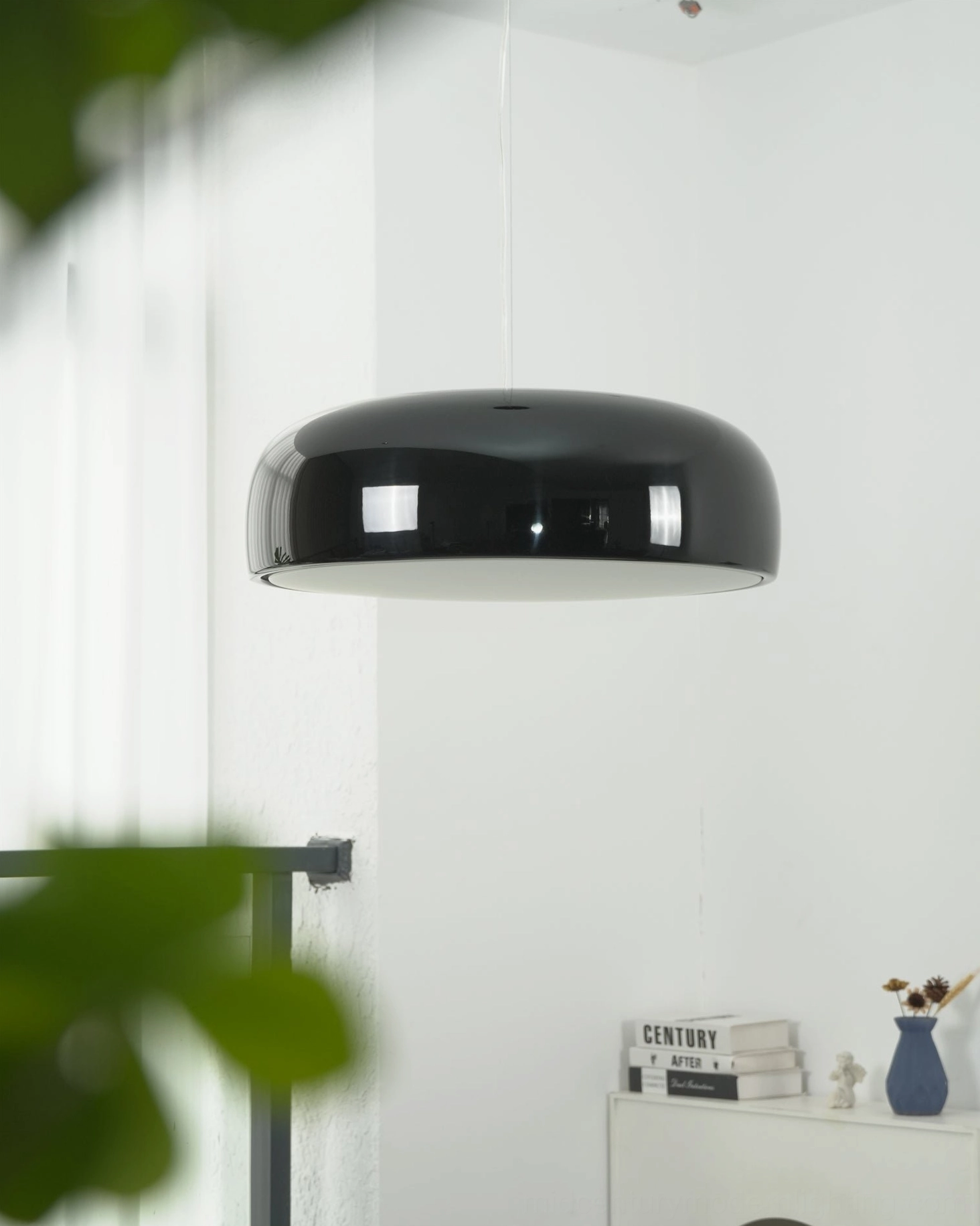 Sleek black Harper dome pendant with foliage foreground in minimalist home hallway corner, architectural pendant lighting design