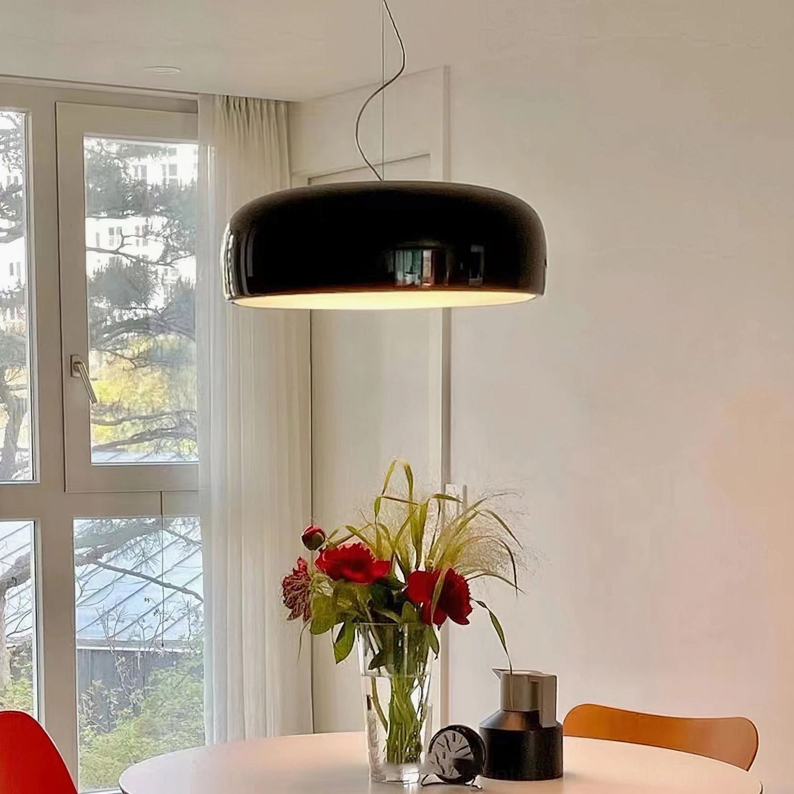 Black Harper dome pendant suspended over Nordic round dining table, table-side eye-level perspective of modern drum-shaped lighting fixture