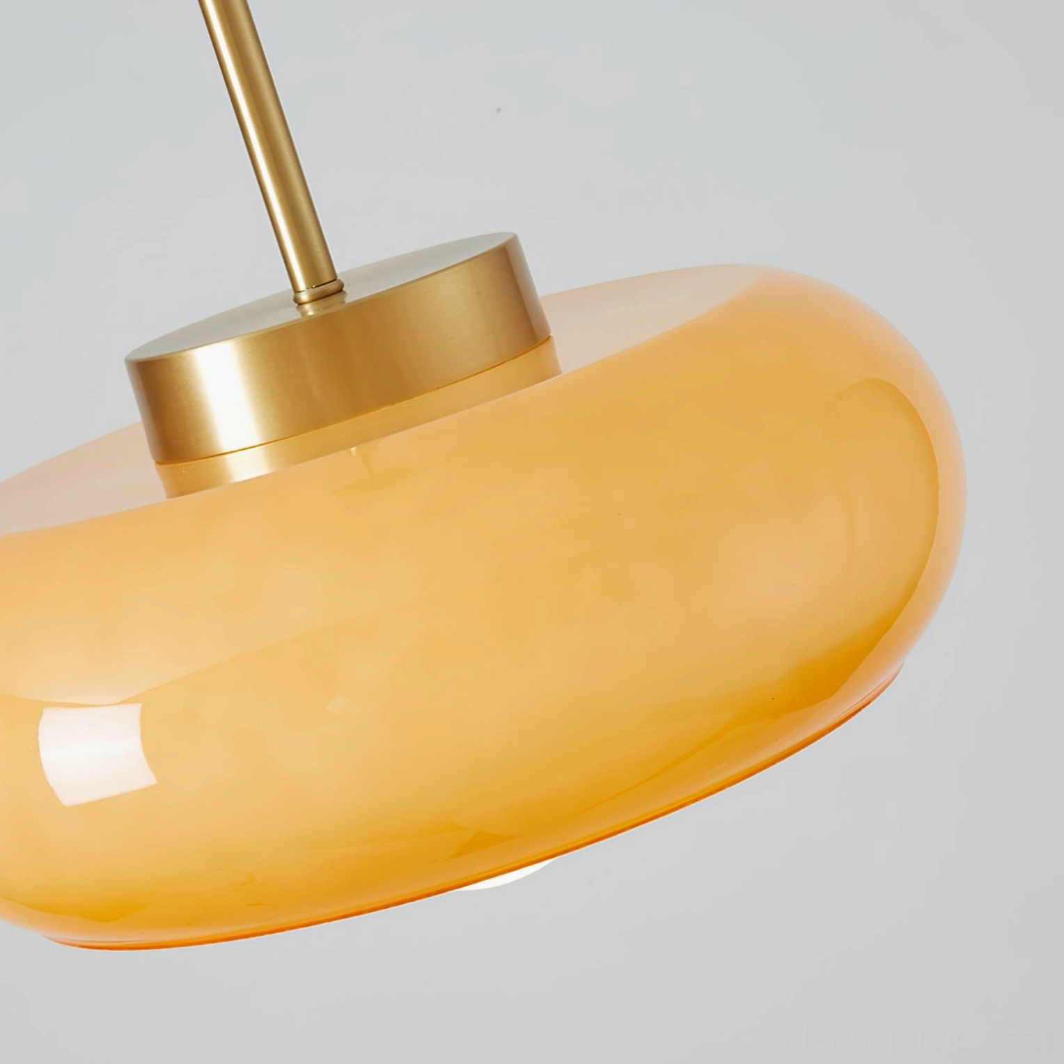 Close-up detail of Harvey pendant lamp brass metal hardware and polished amber glass shade, fixture components