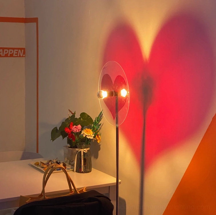 Red heart shadow projection on wall from modern floor lamp positioned near home desk with floral decor
