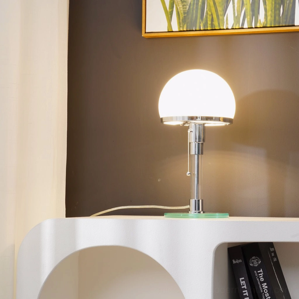 Illuminated chrome hemispherical table lamp on indoor side table with framed wall artwork, soft warm light diffusion