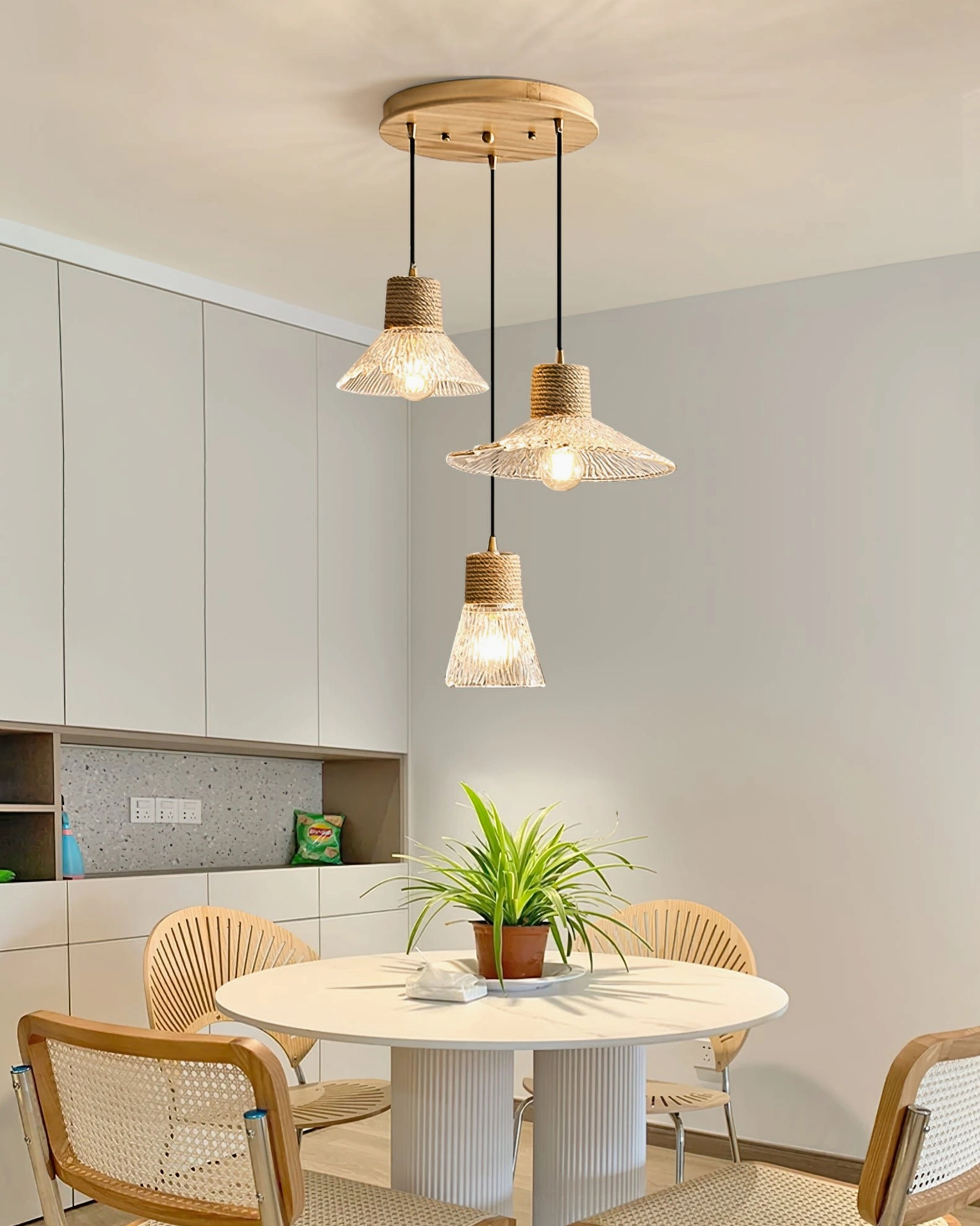 Hemp rope glass pendant suspended at optimal dining height, warm glow on table surface, functional ambient lighting