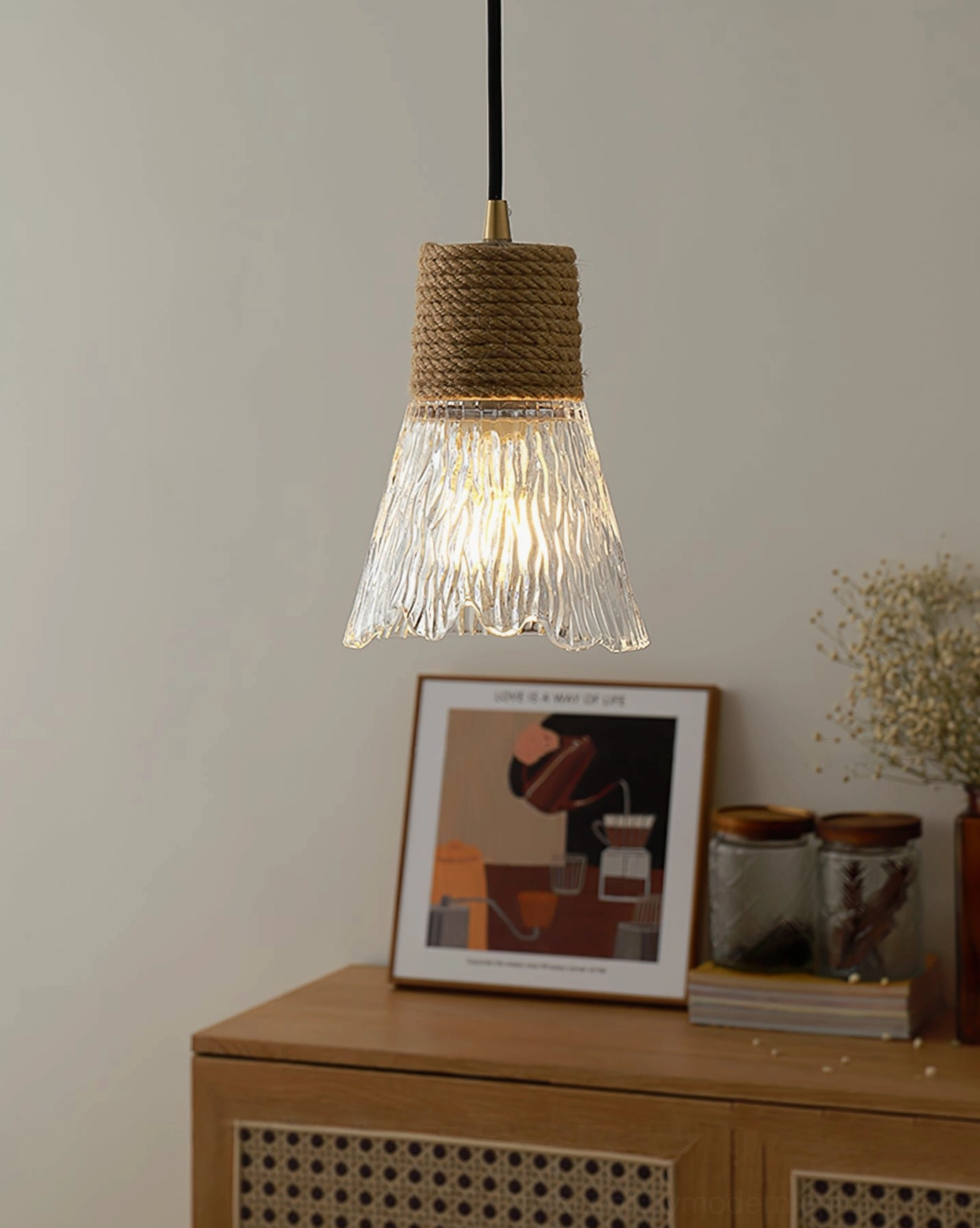 Hemp rope glass pendant lamp beside sideboard with wall art, rustic warm Scandinavian interior design styling