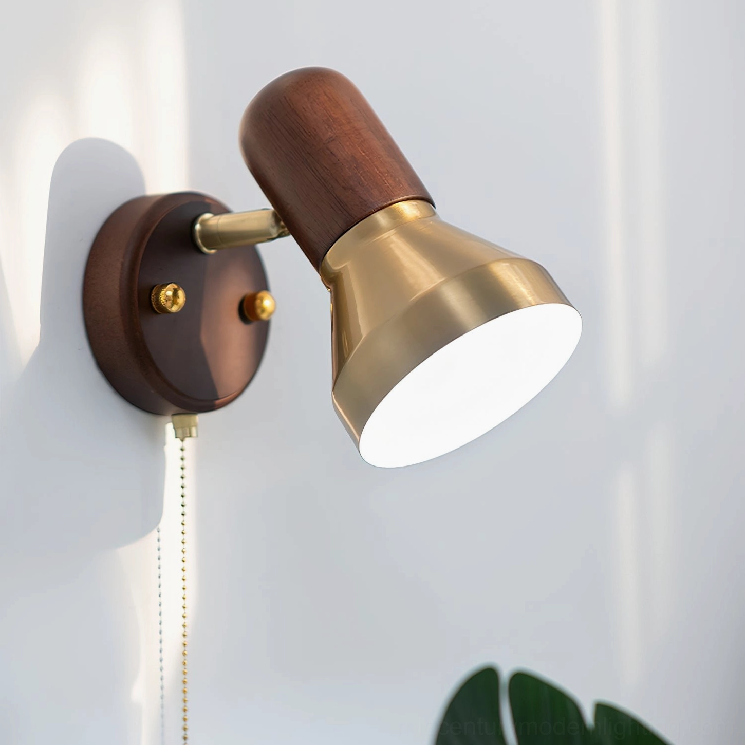 Low angle side view of lit Heron wall sconce showing dual material brass and walnut construction