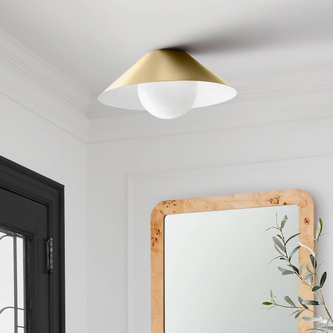Gold finish Hood Coolie minimalist lamp installed in contemporary hallway with mirror and plants