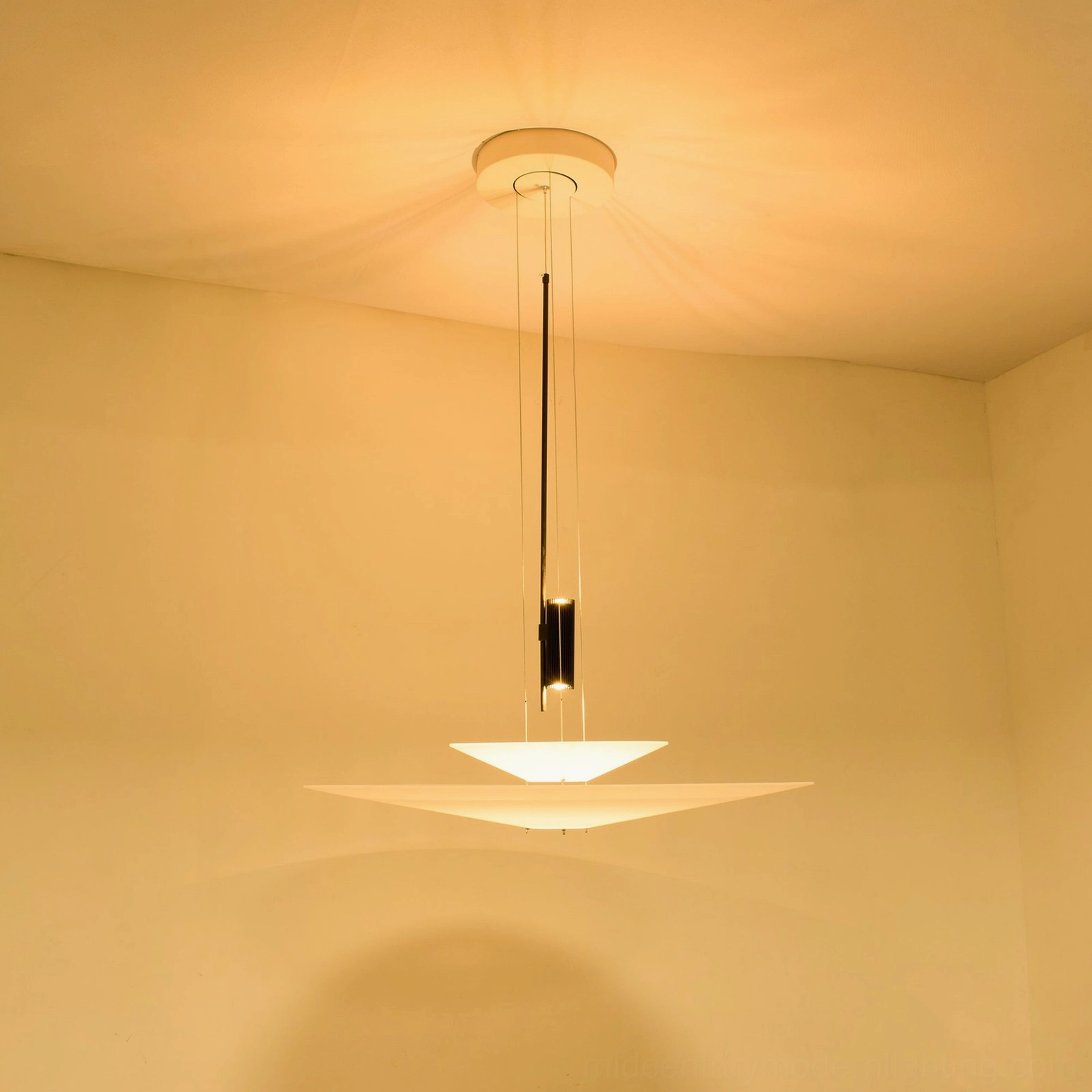 Hover Disc chandelier suspended in warm-toned bedroom with soft ambient glow and black metal rod detail