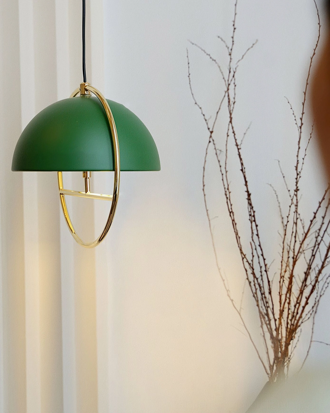 Forest green dome pendant lamp with brass gold frame in Scandinavian interior with sheer curtain and dry branches