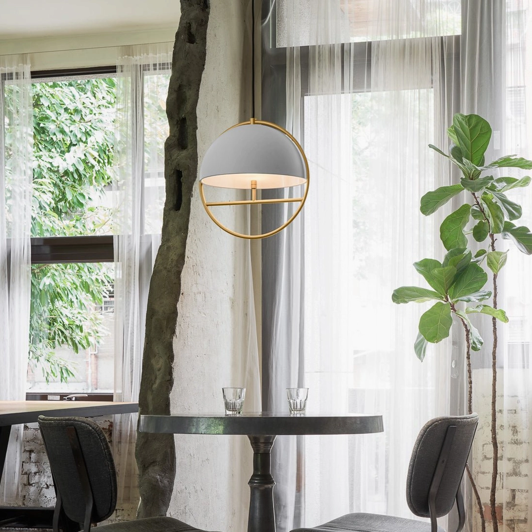Light grey dome pendant lamp with brass frame installed in bright minimalist dining nook with large windows