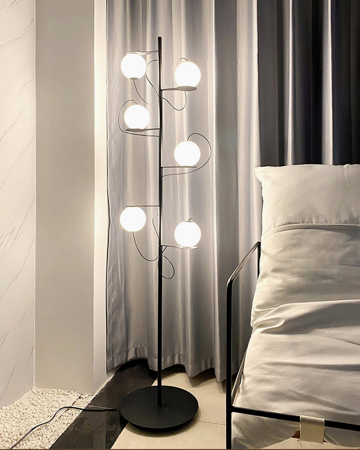 Contemporary multi-globe floor lamp with curved asymmetrical arms in bedroom setting with dark grey curtains and modern décor