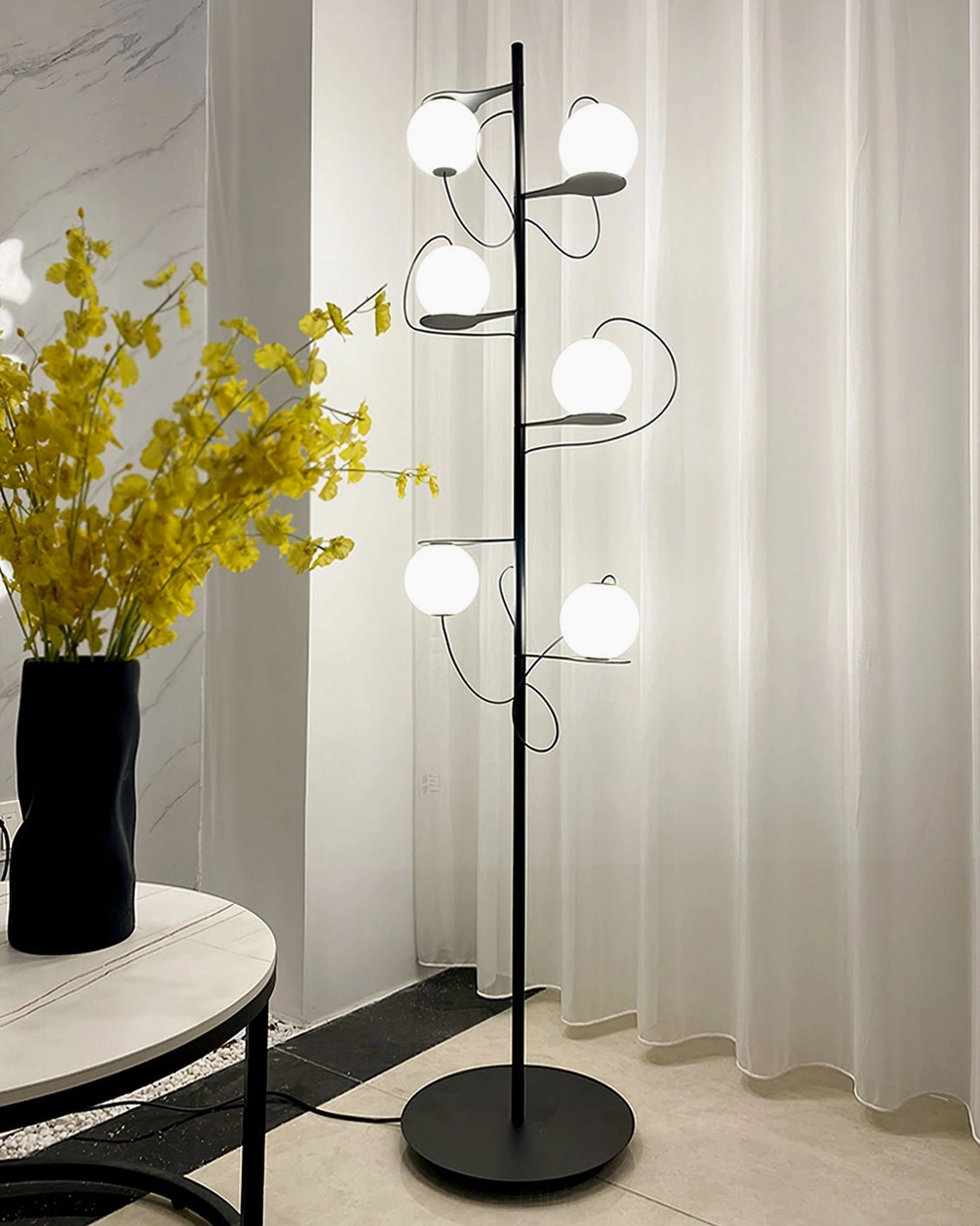 Hubble Bubble floor lamp positioned in bright contemporary minimalist interior corner with round side table and yellow flower arrangement